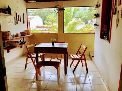 een eetkamer met een tafel en stoelen en een raam bij Pousada Pé na Areia in Serra Grande
