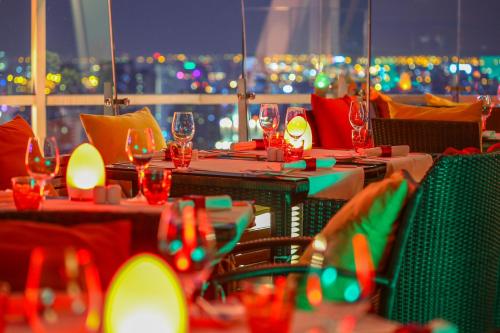 a restaurant with tables with wine glasses and a view of the city at Centara Grand At CentralWorld in Bangkok