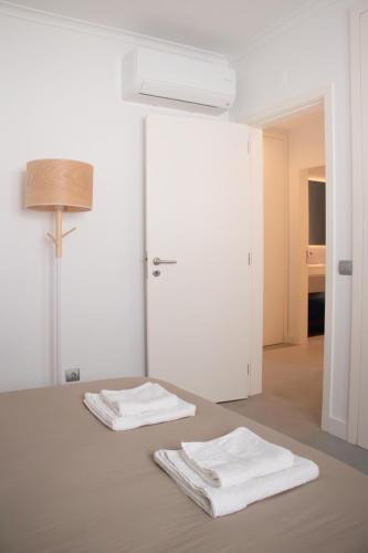two white towels sitting on a table with a mirror at Casa do Sal in Sesimbra