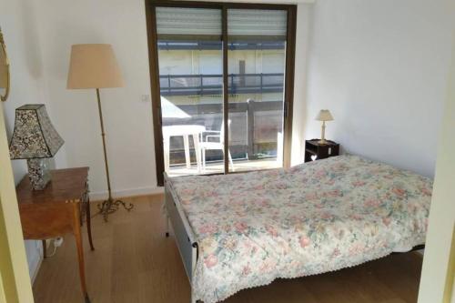 une chambre avec un lit, un bureau et une fenêtre dans l'établissement Spacious apartment in front of the sea, à Deauville