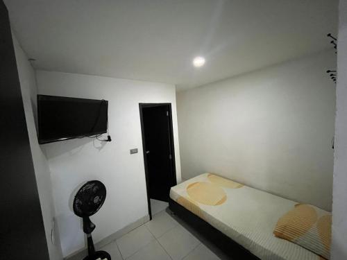 a small bedroom with a bed and a flat screen tv at Hostal Jireth in Floridablanca