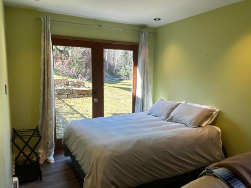 een slaapkamer met een bed en een groot raam bij Kootenay, Lakeside Retreat, Main Floor and Walkout in Nelson