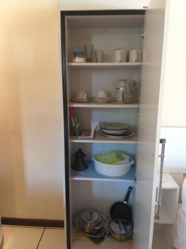a cupboard with dishes and other items in it at Chalé MJF in Monte Verde