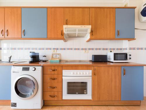 a kitchen with a washing machine and a washer at Casa Maresía Penthouse - Pool & Beach in Sardina