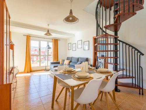 un soggiorno con tavolo, sedie e scala a chiocciola di Casa Maresía Penthouse - Pool & Beach a Sardina