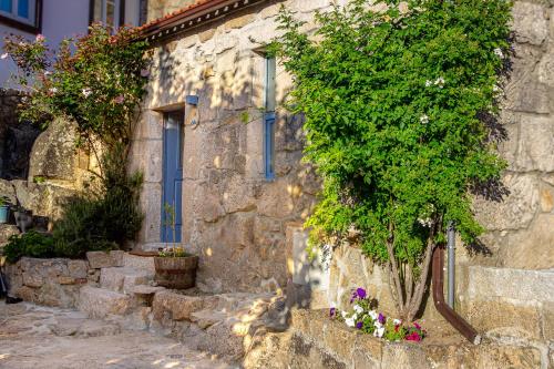 a stone building with plants and flowers in front of it at CelloRico de Sabores - Alojamento Local in Celorico da Beira