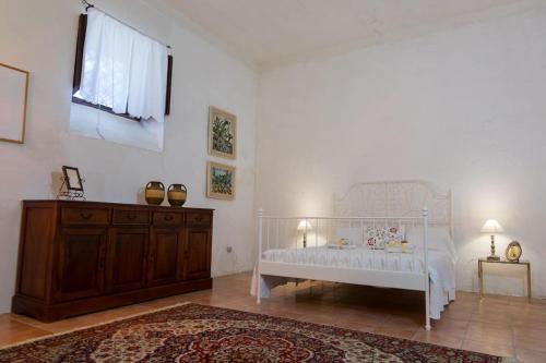 um quarto com uma cama branca e uma cómoda em madeira em Casa di Nonna Maria em Pietraperzia