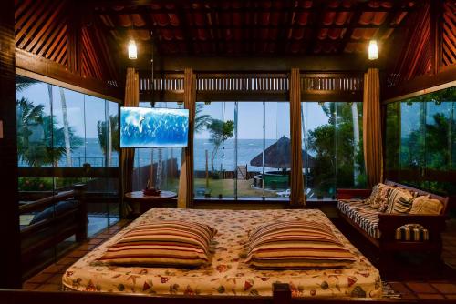 una camera da letto con un letto e una grande finestra di Casa de frente para a praia - Arraial d' Ajuda a Arraial d'Ajuda