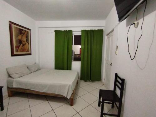 1 dormitorio con cortinas verdes, 1 cama y 1 silla en THE ROYAL GUEST HOUSE Hco, en Huanchaco