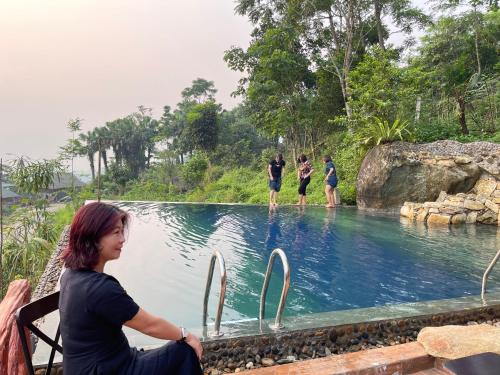 a woman sitting in front of a swimming pool at Pù Luông Sala Homestay in Hương Bá Thước