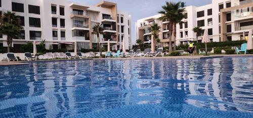 a large swimming pool in front of some buildings at Plage dès nations 2 bedroom apartment with backyard view in Sidi Bouqnadel