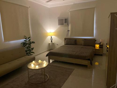 una camera con letto, divano e tavolo di جوهرة الوجه a Al Wajh