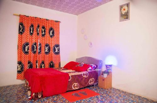 1 dormitorio con 1 cama con manta roja en JaneChill Guest House, en Accra