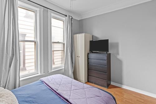 a bedroom with a bed and a dresser with a television at 7BR house 19 ppl DT Windsor WD Free Parking in Windsor