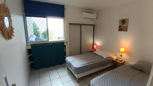 ein kleines Schlafzimmer mit 2 Betten und einem Fenster in der Unterkunft "Le Caraïbe" T3 à Bas du Fort au Gosier à quelques pas de la plage in Le Gosier