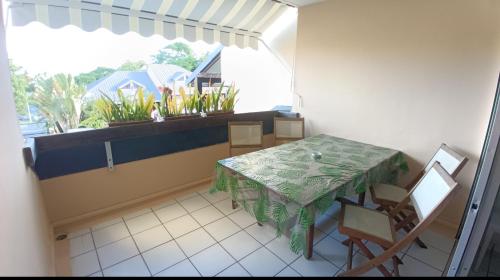 um quarto com uma mesa e cadeiras e uma janela em "Le Caraïbe" T3 à Bas du Fort au Gosier à quelques pas de la plage em Le Gosier