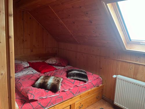 a bed in a wooden room with two pillows on it at Cabana Pastravarul in Topliţa