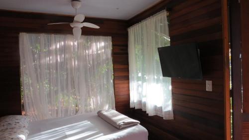 a bedroom with a bed with a ceiling fan and a window at Cabanas sítio Ancestral in Morretes