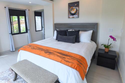 a bedroom with a large bed with an orange and white blanket at Casa De Petrus-All Three Villas in East End
