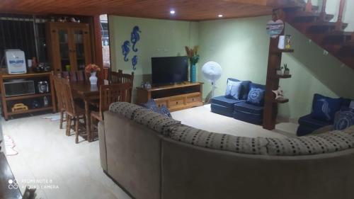 a living room with a couch and a dining room at Apto na praia do Centro Mongaguá ~ Ótima Localização in Mongaguá