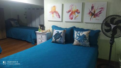a bedroom with a bed with blue sheets and pillows at Apto na praia do Centro Mongaguá ~ Ótima Localização in Mongaguá