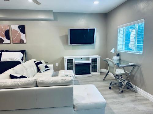 a living room with a white couch and a tv at Corporate Manor in Los Angeles