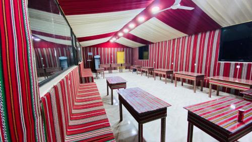 a restaurant with red and white striped walls and tables and benches at Desert Eyes Camp in Wadi Rum