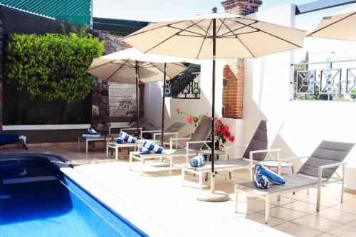 een patio met stoelen en parasols naast een zwembad bij Hotel Borda Cuernavaca in Cuernavaca