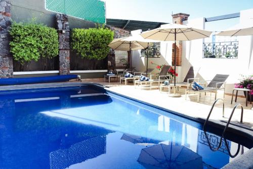 een zwembad met parasols, tafels en stoelen bij Hotel Borda Cuernavaca in Cuernavaca