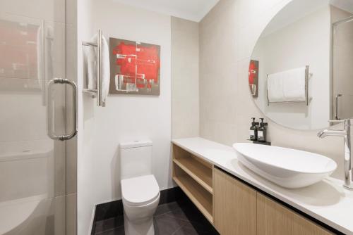 uma casa de banho branca com um lavatório e um WC em CityLife Auckland em Auckland