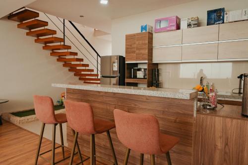a kitchen with a bar with chairs and a staircase at Cajamarca Home Family Centric Parrilla 4BR in Cajamarca