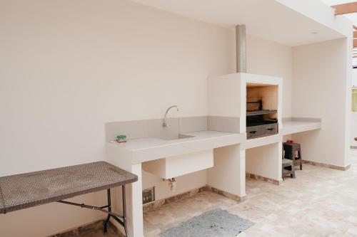 a white kitchen with a sink and a counter at Cajamarca Home Family Centric Parrilla 4BR in Cajamarca