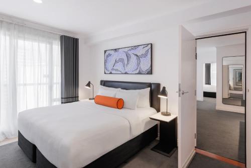 オークランドにあるシティライフ オークランドのベッドルーム(大きな白いベッド、オレンジ色の枕付)