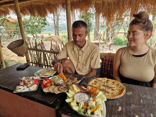 Un uomo e una donna seduti a un tavolo con del cibo di Pemsee's Tree Town - Eco-friendly,Tree house hostel a Sauraha