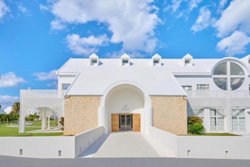 a white house with a blue sky at Pricia Resort Yoron in Yoron
