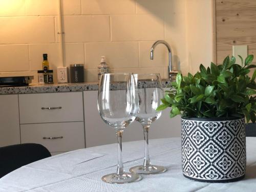 two wine glasses sitting on a table with a vase at Habitations Zenith in Sainte-Anne-de-Beaupré