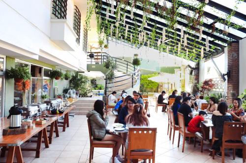 a group of people sitting at tables in a restaurant at Hotel Borda Cuernavaca in Cuernavaca