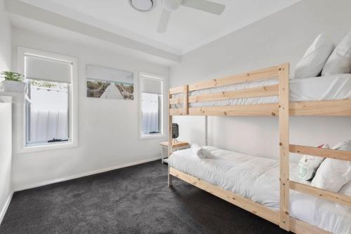 a bedroom with a bunk bed and two windows at LUXURY SEASIDE RETREAT / SUSSEX INLET in Sussex Inlet