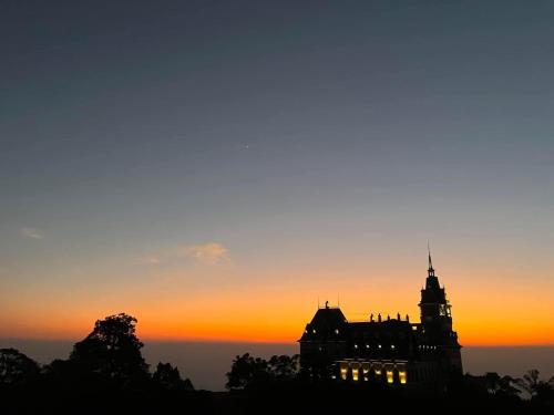 a silhouette of a building with a sunset in the background at Khách Sạn Hùng Trang Hotel in Tam Ðảo