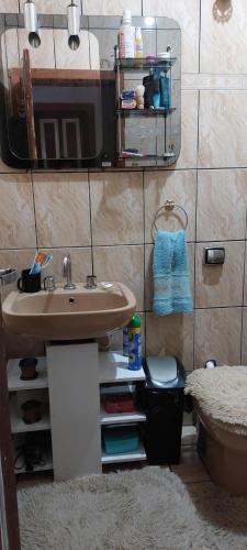 a bathroom with a sink and a tv on a wall at Quarto em casa familiar. in Porto Velho