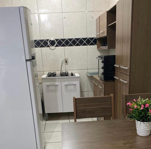 uma pequena cozinha com um lavatório e uma mesa em Casa Rute - Conforto em primeiro lugar! em Fortaleza