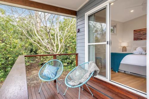 1 Schlafzimmer mit einem Bett und 2 Stühlen auf einem Balkon in der Unterkunft Sahaja Cottage - WENTWORTH FALLS in Wentworth Falls