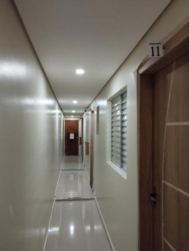 un couloir aux murs blancs et un long couloir dans l'établissement Hotel motel Raiar do Sol santo Amaro, à São Paulo