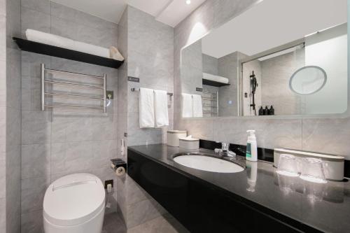 a bathroom with a sink and a toilet and a mirror at Atour X Hotel Ningbo Railway Station North Square in Ningbo