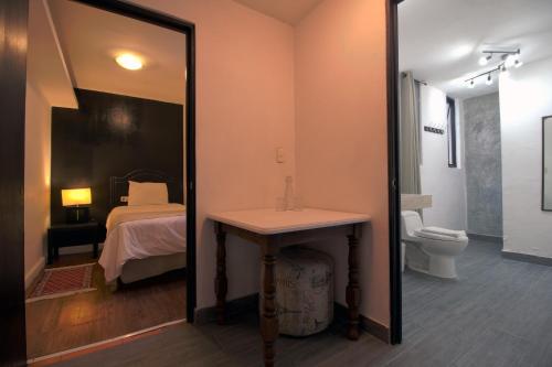 baño con lavabo, cama y espejo en Hotel Punto 79, en San Miguel de Allende