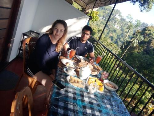 un hombre y una mujer sentados en una mesa con comida en Forest Rawana homestay Ella, en Ella