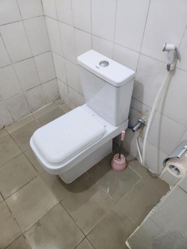 eine weiße Toilette in einem Badezimmer mit einer Zahnbürste in der Unterkunft Expert Location Service in Abidjan
