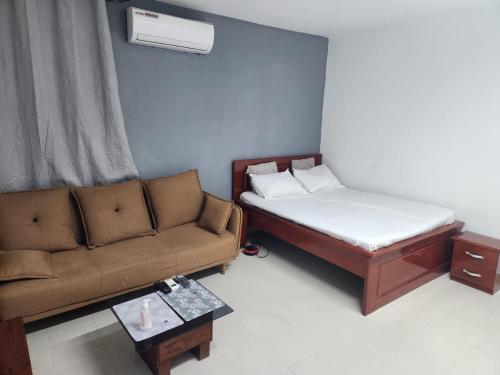 ein kleines Zimmer mit einem Bett und einer Couch in der Unterkunft Expert Location Service in Abidjan