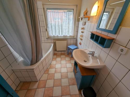 a small bathroom with a tub and a sink at Haus Piratenperle - Hooksiel in Wangerland