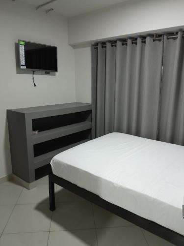 a bedroom with a bed and a desk and a tv at Hotel Singapur in San José